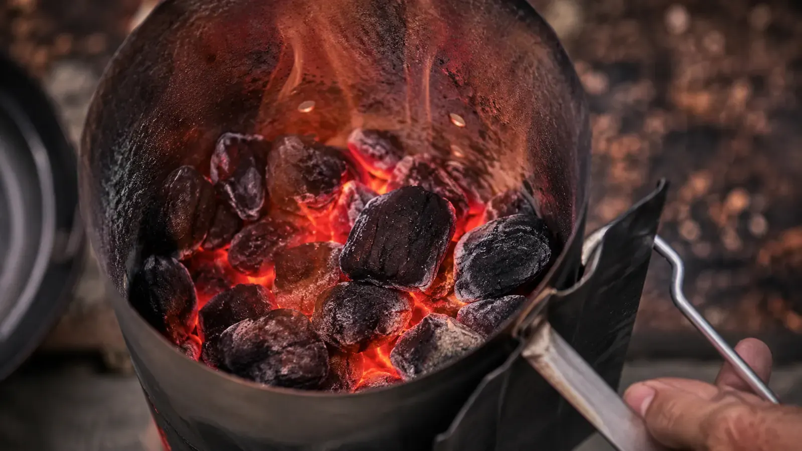 Backyard griller loading briquettes into a Weber chimney starter on a summer evening